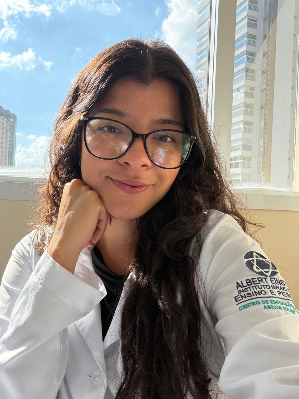 Portrait of Carolina Silva smiling, wearing her white coat by the window